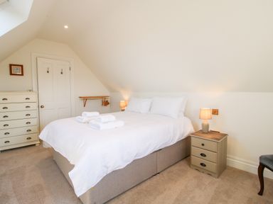 A bedroom with a double bed with white bedding two bedside tables with lamps a chest of drawers and a door at Daniels Farmhouse in Claines