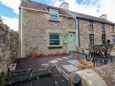 An outdoor view of the exterior of a house with seating at 2 Strand Cottages in Laugharne