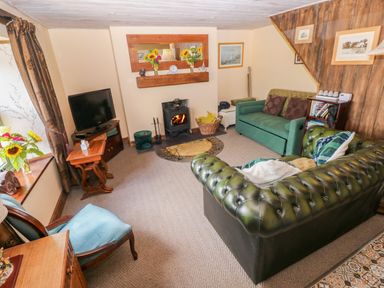 A living room with furniture and a fireplace at 2 Strand Cottages in Laugharne