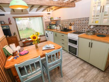 A kitchen with a table and chairs at 2 Strand Cottages in Laugharne