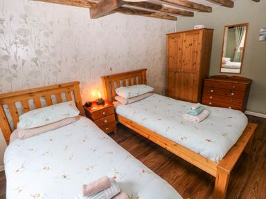 A bedroom with two single beds and a wardrobe at 2 Strand Cottages in Laugharne