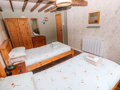 A bedroom with two beds and wooden furniture at 2 Strand Cottages Laugharne