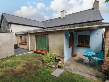 An outdoor view of a cottage with table and chairs at 2 Strand Cottages in Laugharne