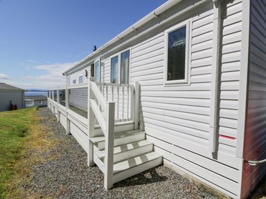 The exterior of a white mobile home with steps leading to a door and a long glass railing at Bethany's Retreat in Wemyss Bay
