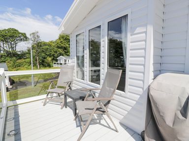 A balcony with two chairs a small table and a covered barbecue at Bethany's Retreat in Wemyss Bay