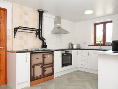 A kitchen with white cabinets black countertops a stove oven toaster kettle and a window at West Lee in Bude