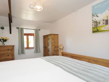 A bedroom with a wooden bed a dresser a wardrobe and a window with curtains at West Lee in Bude