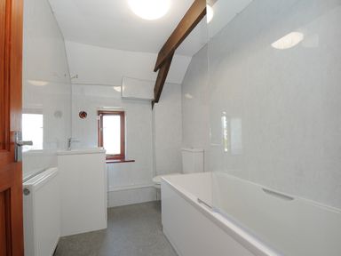 A bathroom with a bathtub toilet sink window radiator and exposed wooden beam at West Lee in Bude
