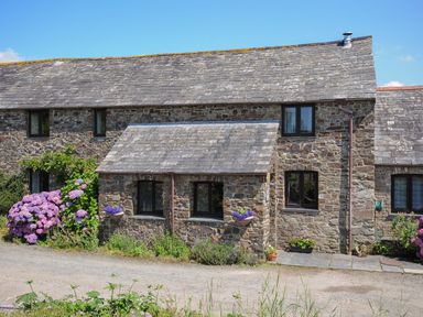 A stone house with a tiled roof and flowers outside at West Lee in Bude