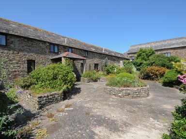 A stone courtyard with raised flower beds and shrubs at West Lee in Bude