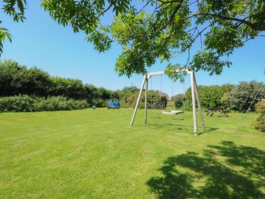 A garden with a swing set a picnic table and a toy tractor at West Lee in Bude