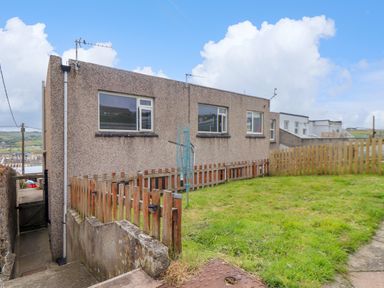 The exterior of a residential building with pebble dash walls a small fenced yard and grass at Small Hillman in Perranporth