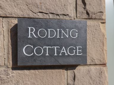 A stone plaque with the words Roding Cottage on a stone wall at Roding Cottage in Egton