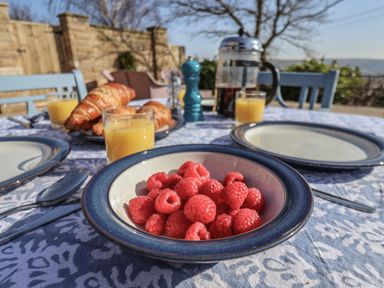 A table set with a bowl of raspberries plates croissants glasses of orange juice and a French press coffee maker at Roding Cottage Egton
