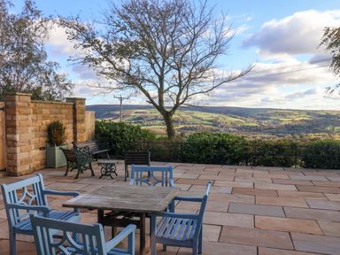 An outdoor patio with a table and chairs overlooking a valley at Roding Cottage in Egton
