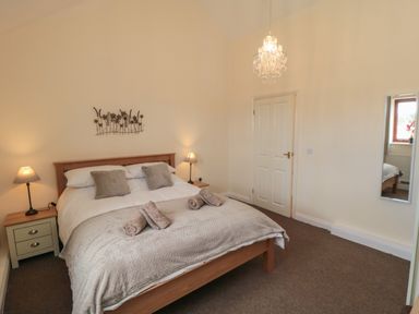 A bedroom with a double bed two bedside tables with lamps and a wall mirror at Curlew Cottage near Filey