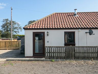An exterior view of a single-story house with a tiled roof a wooden door and a wooden fence near Filey