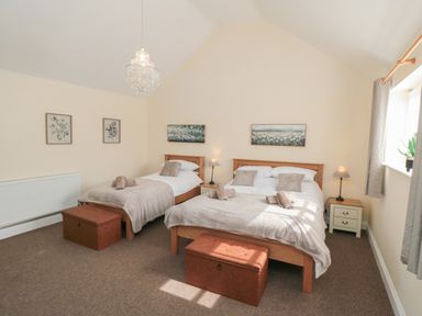 A bedroom with two beds bedside tables lamps and framed pictures at Curlew Cottage near Filey