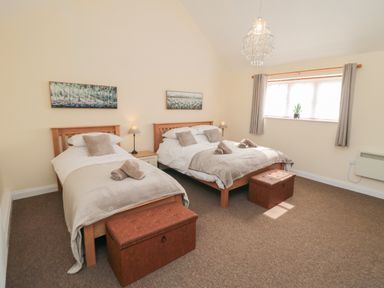 A bedroom with two beds a window bedside tables lamps and storage benches at Curlew Cottage near Filey