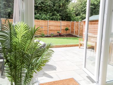 A view of a garden with a wooden fence patio plants and outdoor seating at Pine Cottage in Wrentham