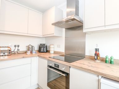 A kitchen with white cabinets wooden countertop stove oven toaster kettle coffee machine and condiments at Pine Cottage in Wrentham