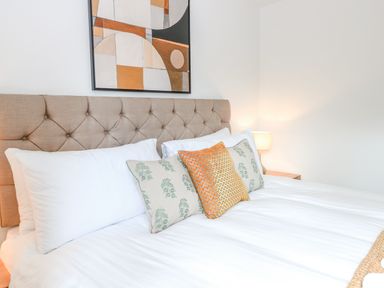 A bedroom with a tufted headboard and decorative pillows at Pine Cottage in Wrentham