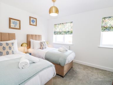 A bedroom with two single beds with blue throws and rolled towels at Pine Cottage in Wrentham