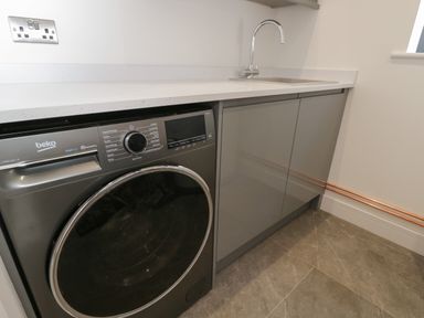 A laundry room with a washing machine sink and cabinet at The Hay Barn in Huntley