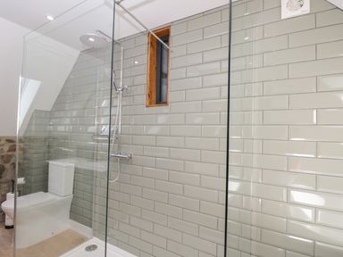A bathroom with a glass enclosed shower and a toilet at The Hay Barn in Huntley