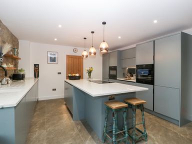 A kitchen with an island and bar stools at The Hay Barn in Huntley