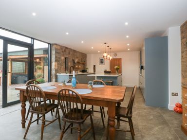 A kitchen with a dining table and chairs at The Hay Barn in Huntley