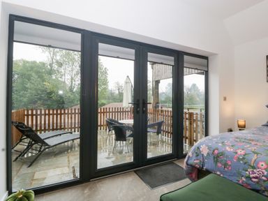 A bedroom with sliding glass doors leading to a deck at The Hay Barn in Huntley
