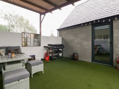 An outdoor seating area with a table and barbecue grill at The Hay Barn in Huntley