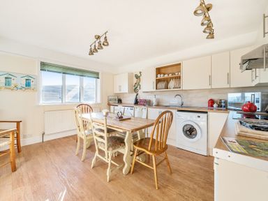 A kitchen with a dining table and chairs a washing machine and cabinets at Bayview in Overcombe near Preston