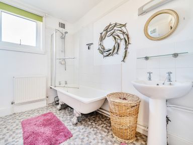 A bathroom with a bathtub shower sink wicker laundry basket and fish wall art at Bayview in Overcombe near Preston