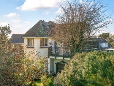 A house with a tiled roof and a balcony surrounded by bushes and trees at Bayview in Overcombe near Preston