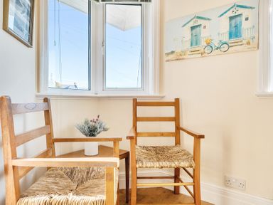 A corner with two wooden chairs a small table with a plant and windows with blinds at Bayview in Overcombe near Preston