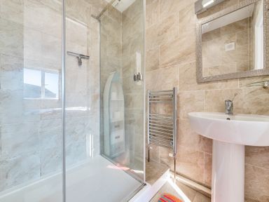 A bathroom with a shower enclosure a pedestal sink a heated towel rail and a mirror at Bayview in Overcombe near Preston