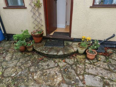 An entrance with flower pots and a doormat at Bridge Cottage in Budleigh Salterton