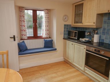 A kitchen with a window and bench seating at Bridge Cottage in Budleigh Salterton