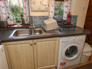 A kitchen with a sink and washing machine at Bridge Cottage Budleigh Salterton