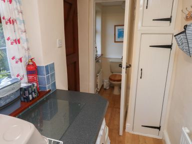 A utility room with a kitchen counter and bathroom door at Bridge Cottage in Budleigh Salterton