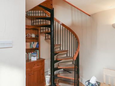 A staircase with a bookshelf and cabinet at Bridge Cottage Budleigh Salterton