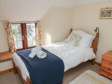 A bedroom with a bed and window at Bridge Cottage in Budleigh Salterton