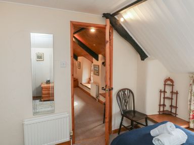A bedroom with a mirror and chair at Bridge Cottage Budleigh Salterton