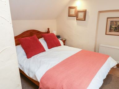 A bedroom with a bed and framed pictures at Bridge Cottage in Budleigh Salterton
