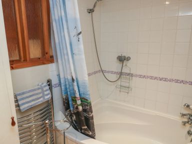A bathroom with a bathtub and shower at Bridge Cottage in Budleigh Salterton