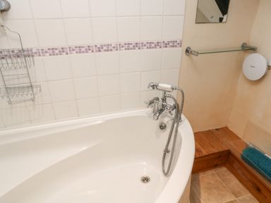 A bathroom with a bathtub and soap rack at Bridge Cottage in Budleigh Salterton