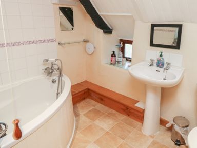 A bathroom with a bath tub and sink at Bridge Cottage in Budleigh Salterton