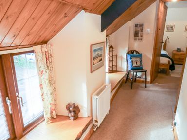 A hallway with a chair and window at Bridge Cottage in Budleigh Salterton